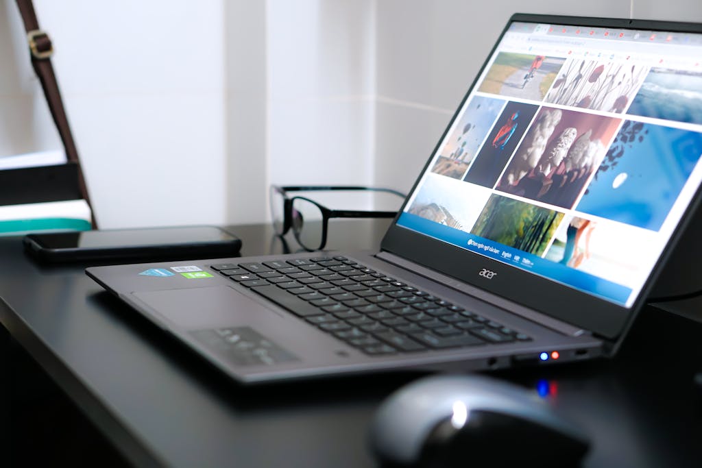 A sleek laptop on a desk with glasses and mouse, ideal for tech or business themes.